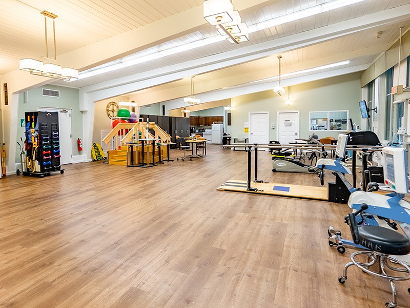 A spacious fitness studio with various exercise equipment and a wooden floor.