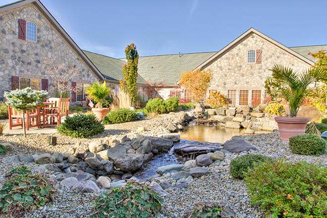 A picturesque stone house with a beautifully landscaped garden and a small pond.