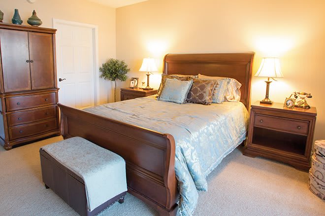 A cozy bedroom featuring a wooden bed with decorative pillows, nightstands with lamps, and a comfortable ambiance.