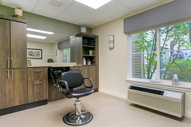 A modern salon interior with a styling chair and large mirror.
