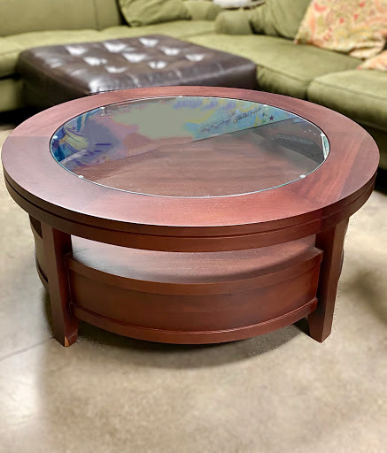 A stylish round coffee table featuring a wooden frame and a glass top, perfect for any living room.