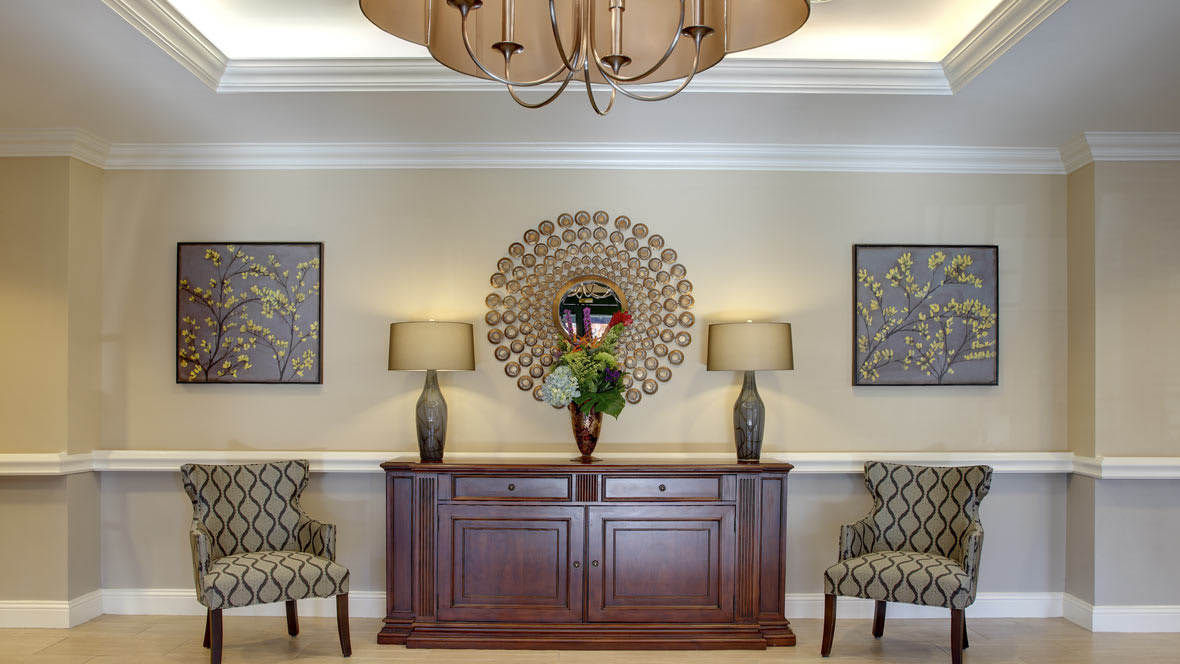 Elegant interior design featuring a wooden cabinet, decorative mirror, lamps, and patterned chairs.