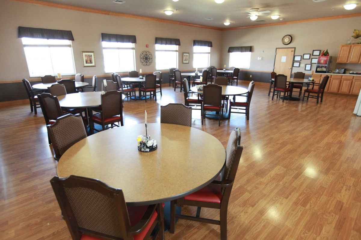 An empty dining room with multiple round tables and chairs arranged neatly.