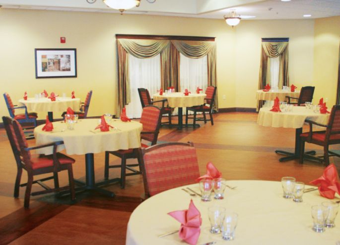 A well-arranged dining room with round tables, red napkins, and stylish decor.