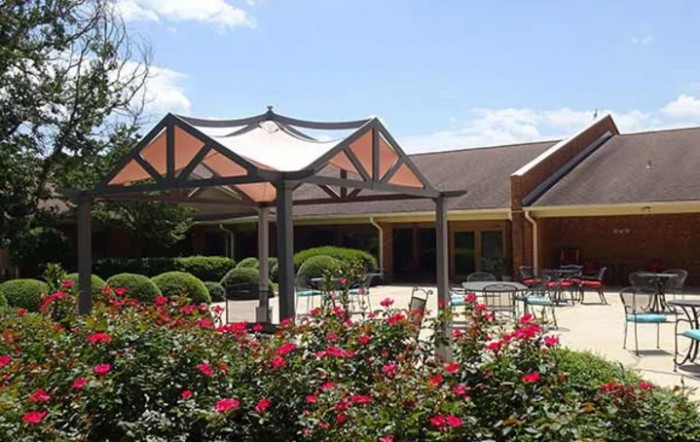 A scenic outdoor area featuring a gazebo surrounded by vibrant flowers and greenery.