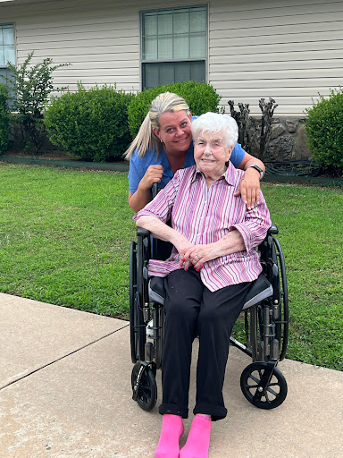 A joyful moment shared between a caregiver and an elderly person enjoying time outdoors.