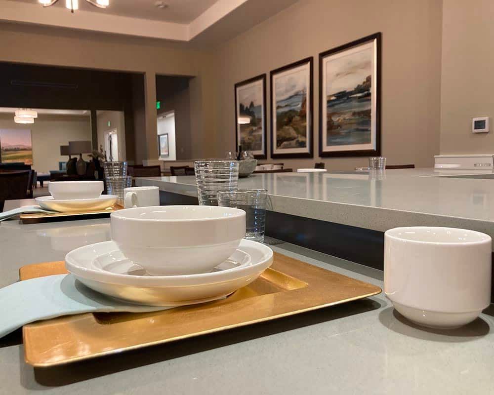 A modern dining room table set with white dishes and cups, accented by elegant artwork on the walls.