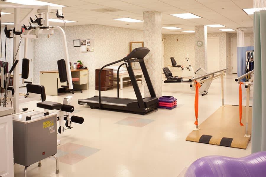 A well-equipped fitness and rehabilitation center with various exercise machines, including a treadmill.