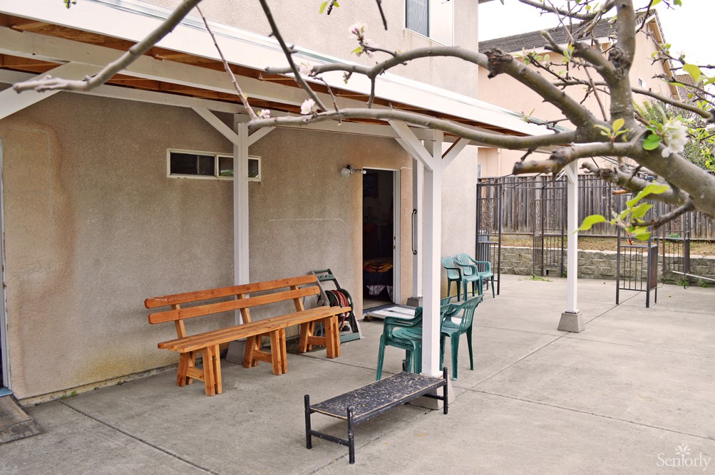 A backyard patio with a variety of outdoor seating options under a pergola.