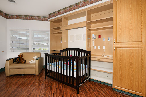 A cozy nursery featuring a dark wooden crib, modern shelving, and comfortable seating.