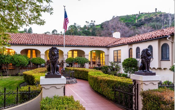 A charming house with a well-manicured garden, featuring a prominent statue and an American flag.