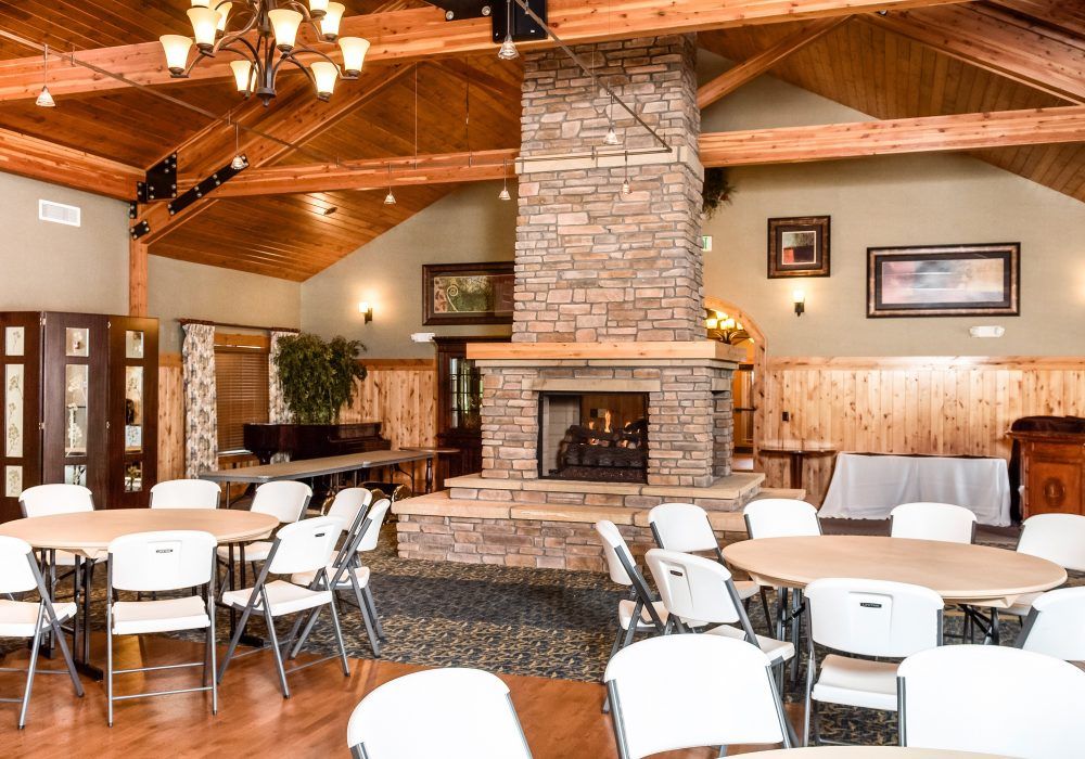 A cozy dining area with a central stone fireplace and wooden ceiling.