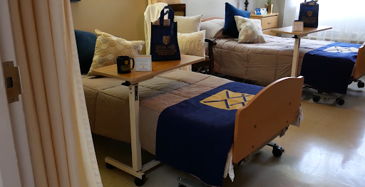 A cozy shared room featuring comfortable beds, decorative pillows, and a versatile table.