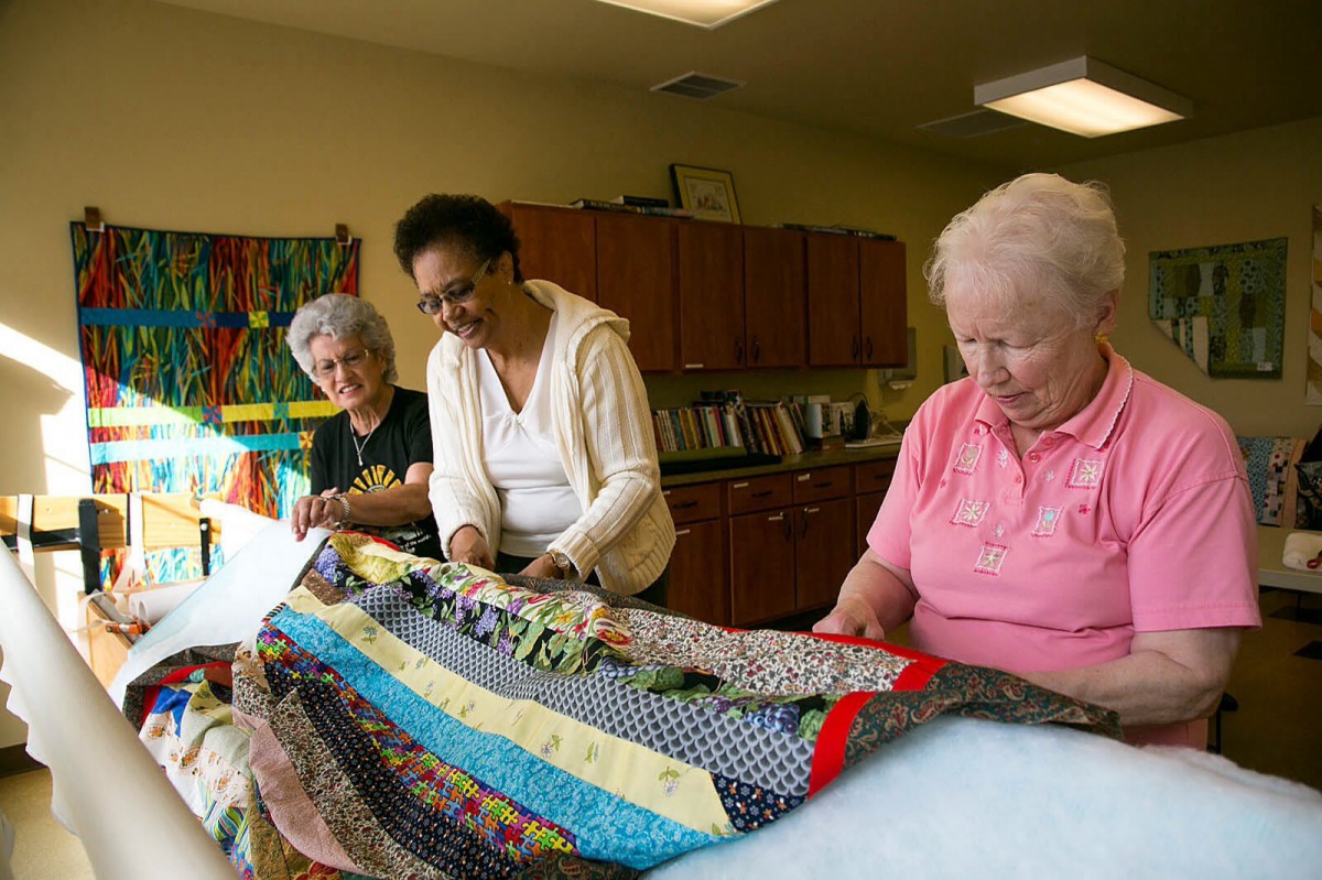 A group of seniors engaged in quilting together at a community center.