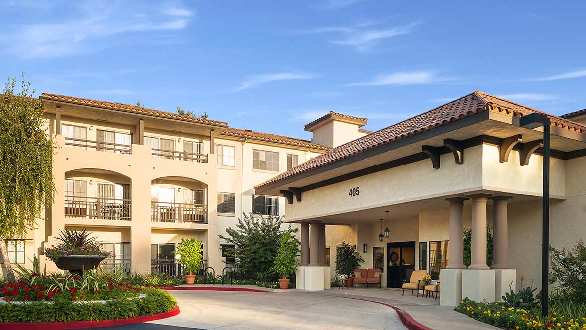 Exterior view of a residential building with an entrance and landscaped surroundings.