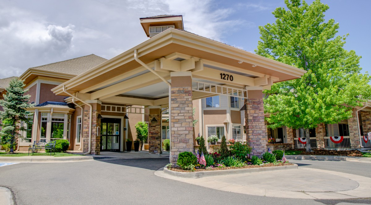 Exterior view of a building entrance with an awning and landscaped surroundings.