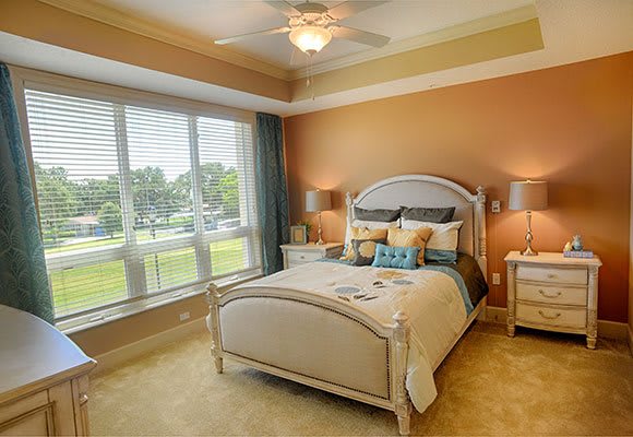 A cozy and elegantly decorated bedroom with a large window allowing natural light to illuminate the space.