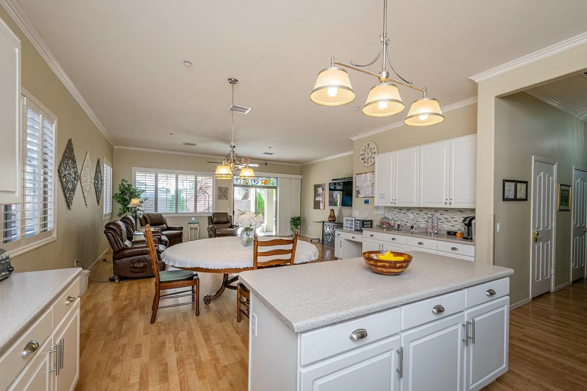 A spacious open-concept kitchen and living area with modern white cabinetry and ample natural lighting.