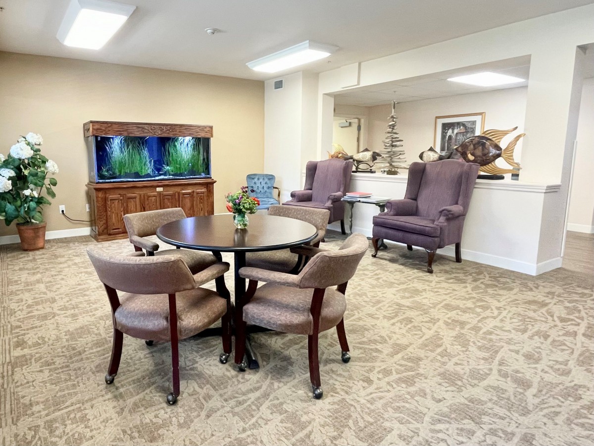 A cozy living room interior with an aquarium, round table, and comfortable seating.