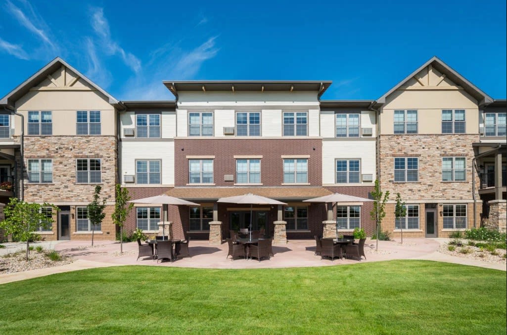 A residential building with a well-maintained lawn and outdoor seating area.