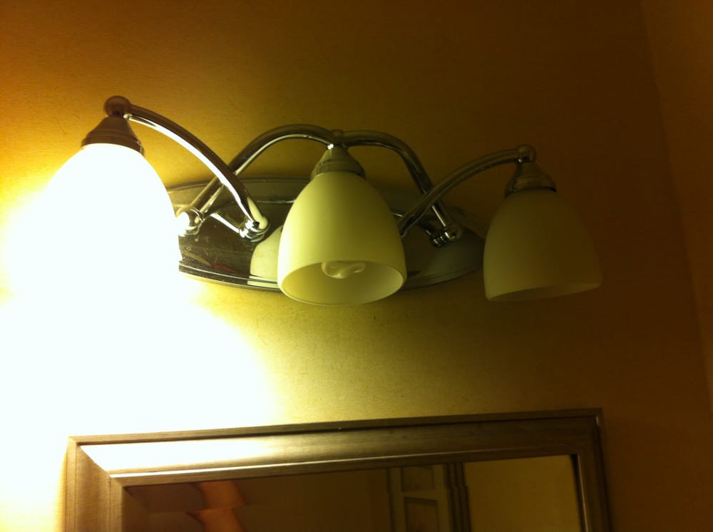 Bathroom light fixture with three bulbs above a mirror.