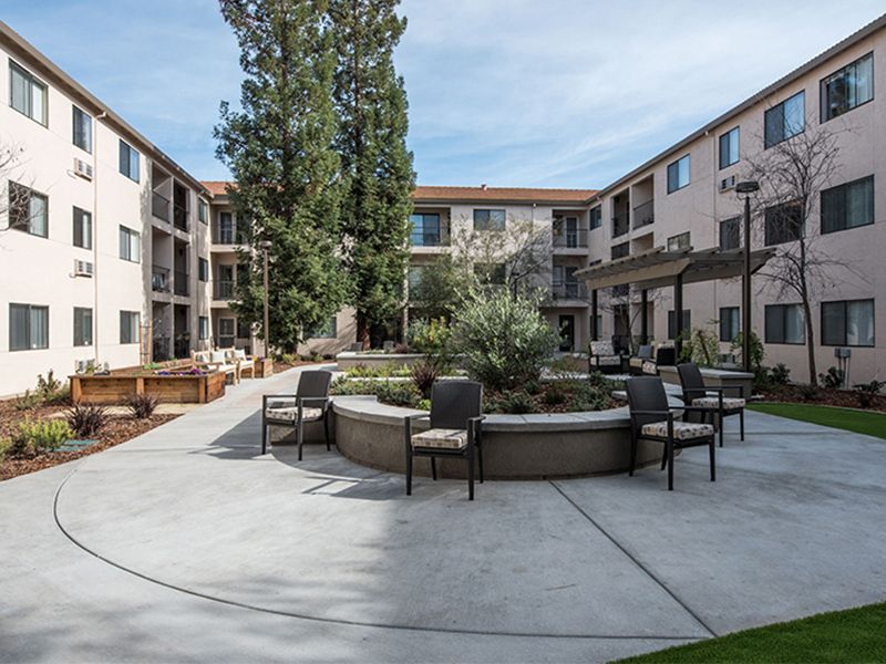 A modern apartment complex courtyard with outdoor seating and landscaping.