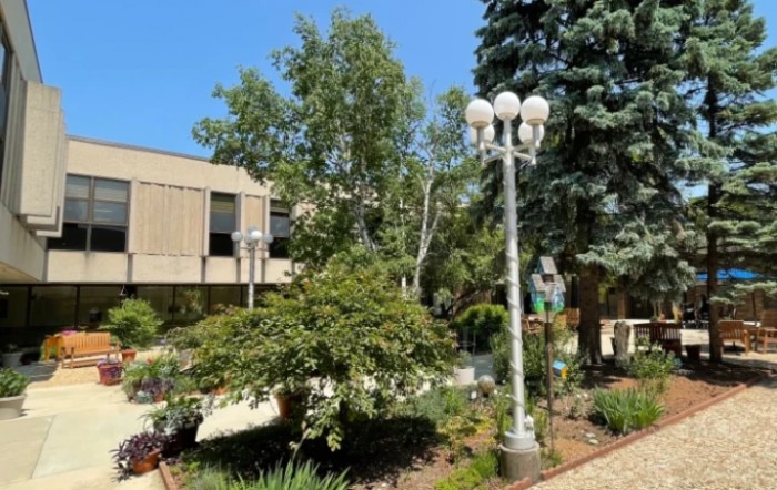 A landscaped area with trees and a lamp post outside a building.