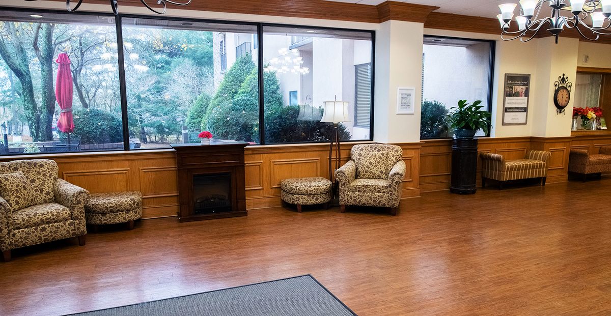 Cozy lobby area with an armchair, ottoman, and large windows overlooking greenery.