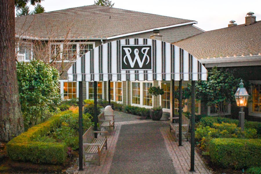 Entrance to a building with a striped awning and landscaped garden.