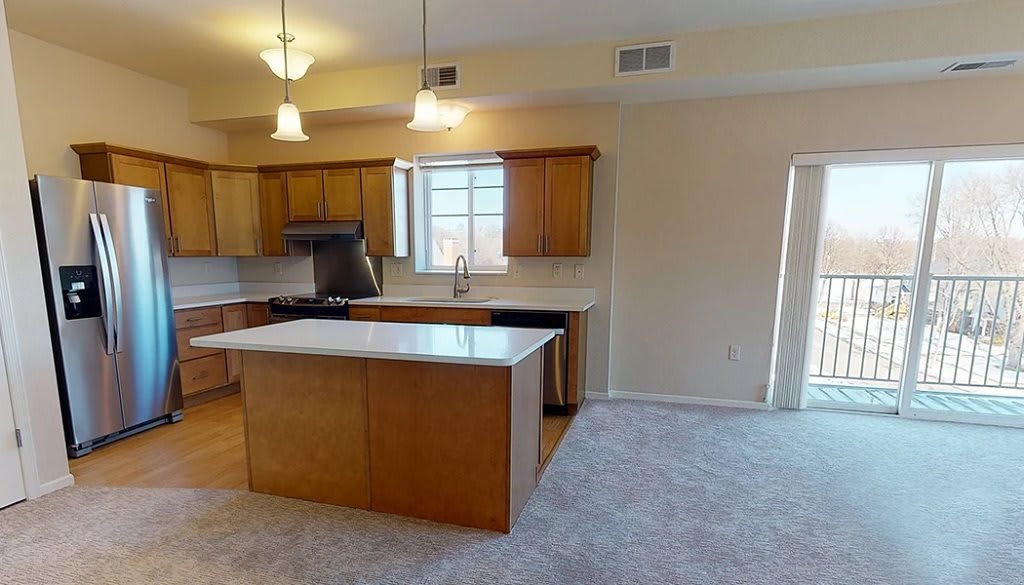 A modern kitchen with wooden cabinets, a central island, and hanging lights.
