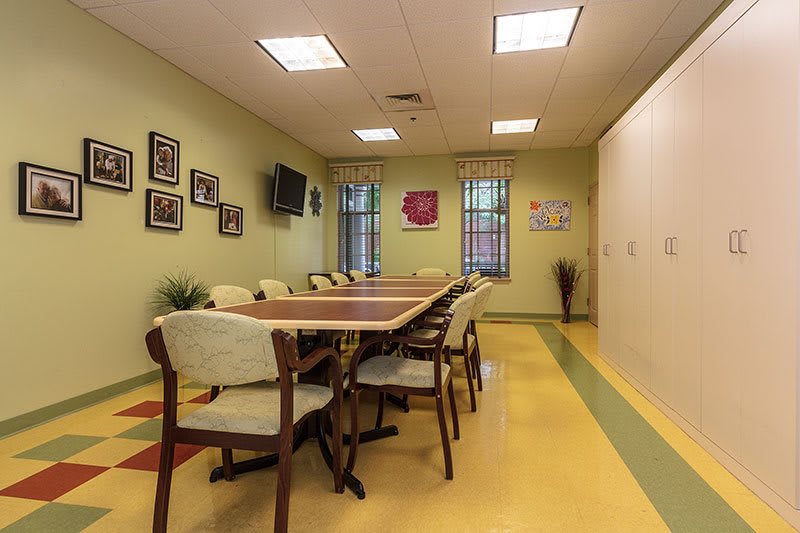 A well-lit conference room with a long table, surrounded by chairs, and decorated walls.