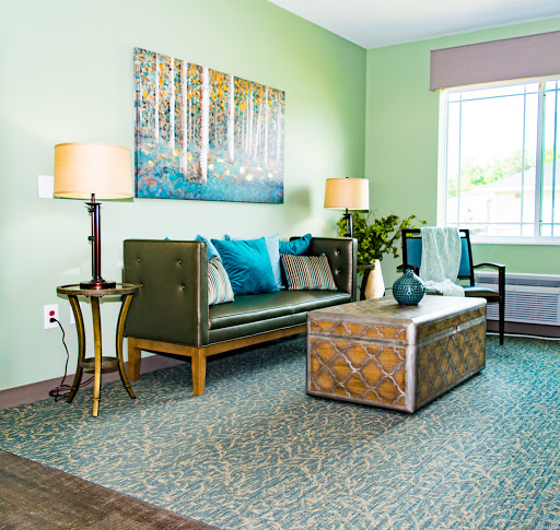A stylish living room featuring a green color palette, modern furnishings, and artwork.