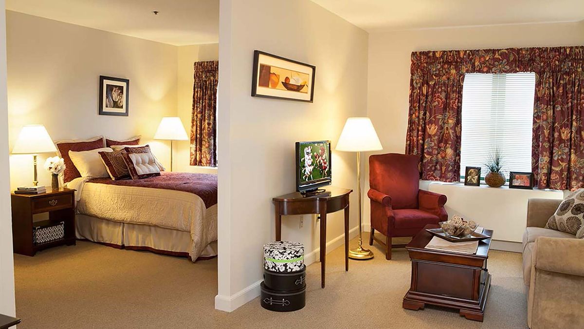 A cozy hotel room with a separate bedroom and living area, featuring traditional furniture and warm lighting.