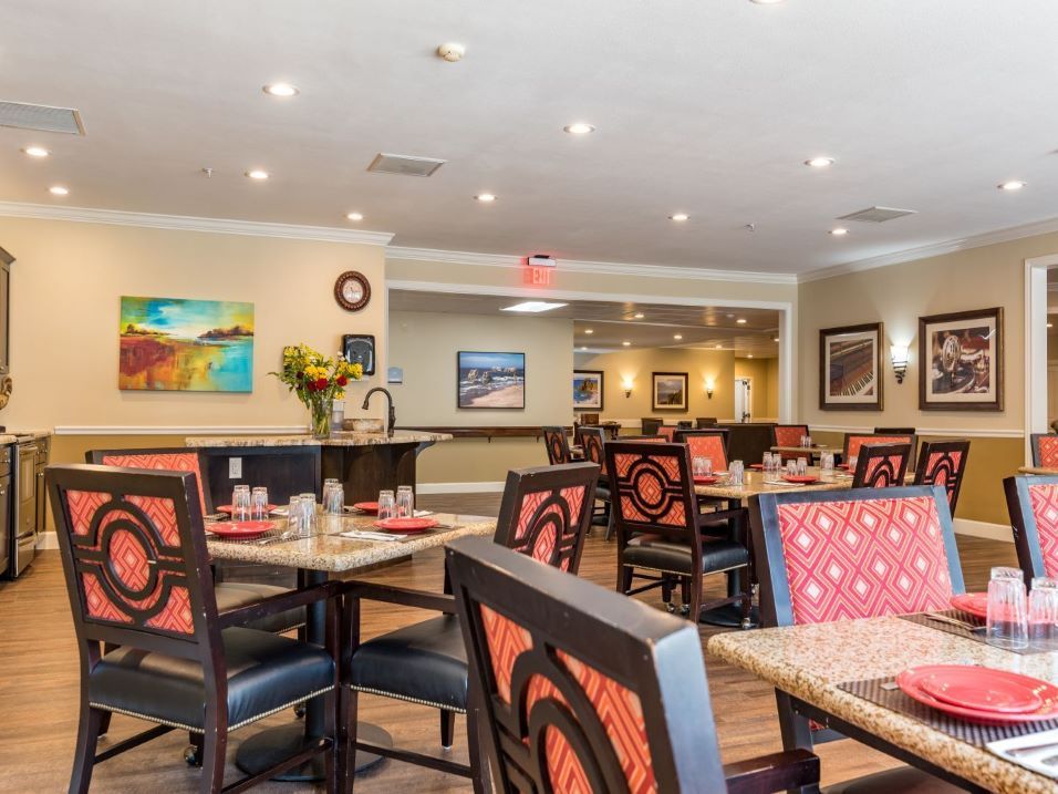 An inviting restaurant dining area with neatly arranged tables and chairs, featuring vibrant artwork on the walls.