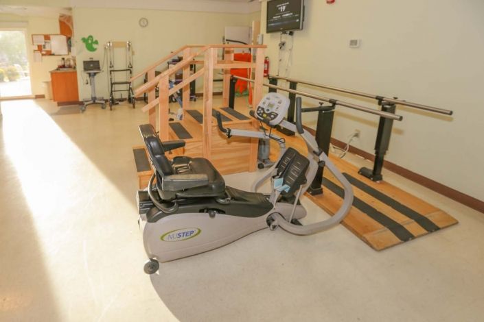 A physical therapy room equipped with exercise machines and parallel bars for rehabilitation.