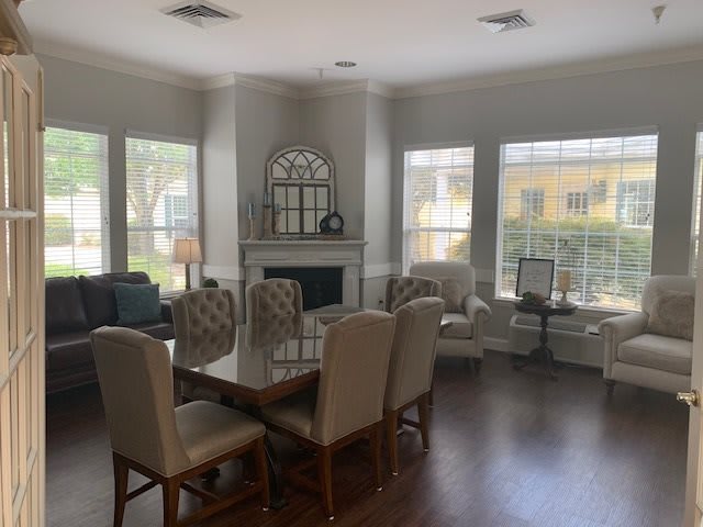 A bright and spacious living room with a dining area, featuring large windows, a fireplace, and elegant furniture.