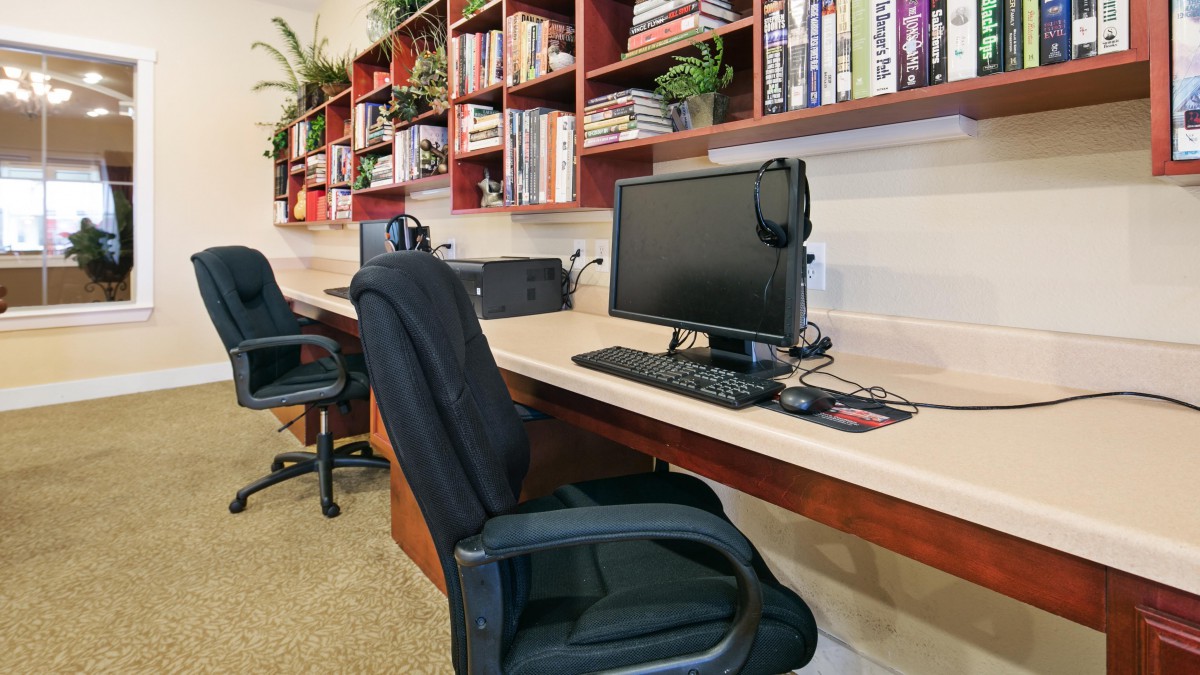 A modern office workspace with computers and bookshelves.