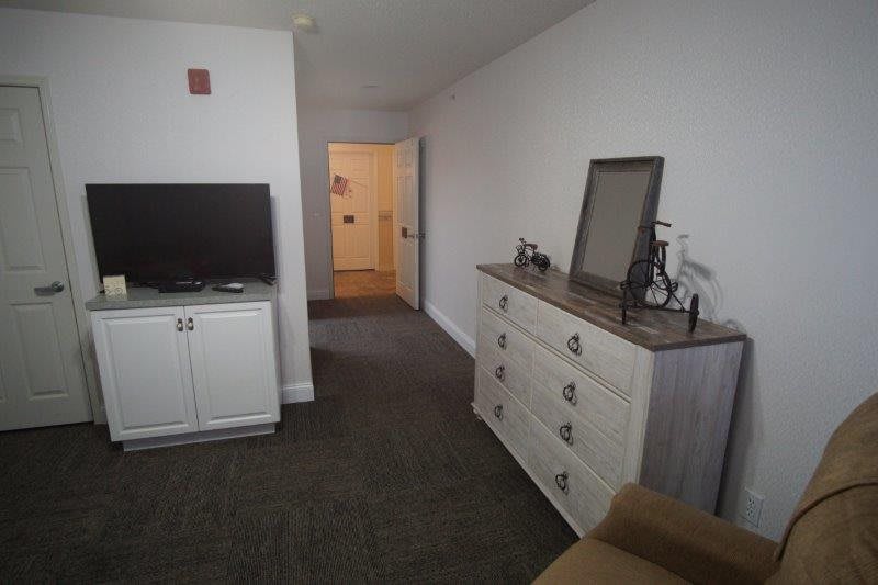 A cozy living room with a television and a dresser.