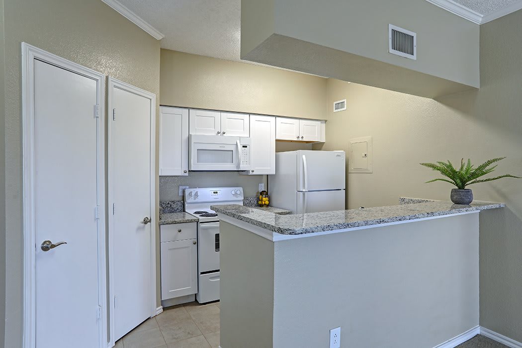 A modern apartment kitchen with white cabinets and appliances.