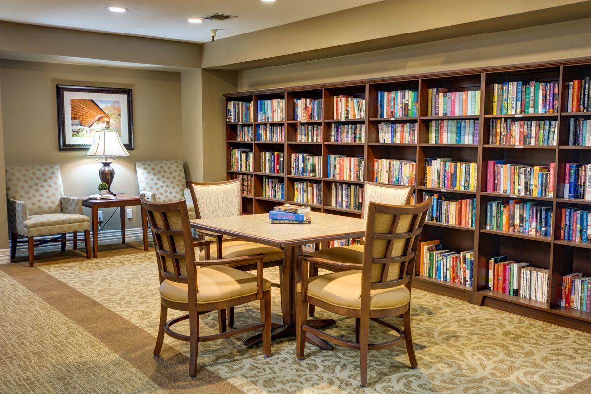 A cozy reading area with a table and chairs surrounded by bookshelves in a library.