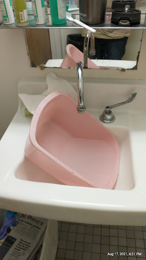 A pink basin awkwardly positioned in a sink, showcasing an unconventional use of kitchen space.