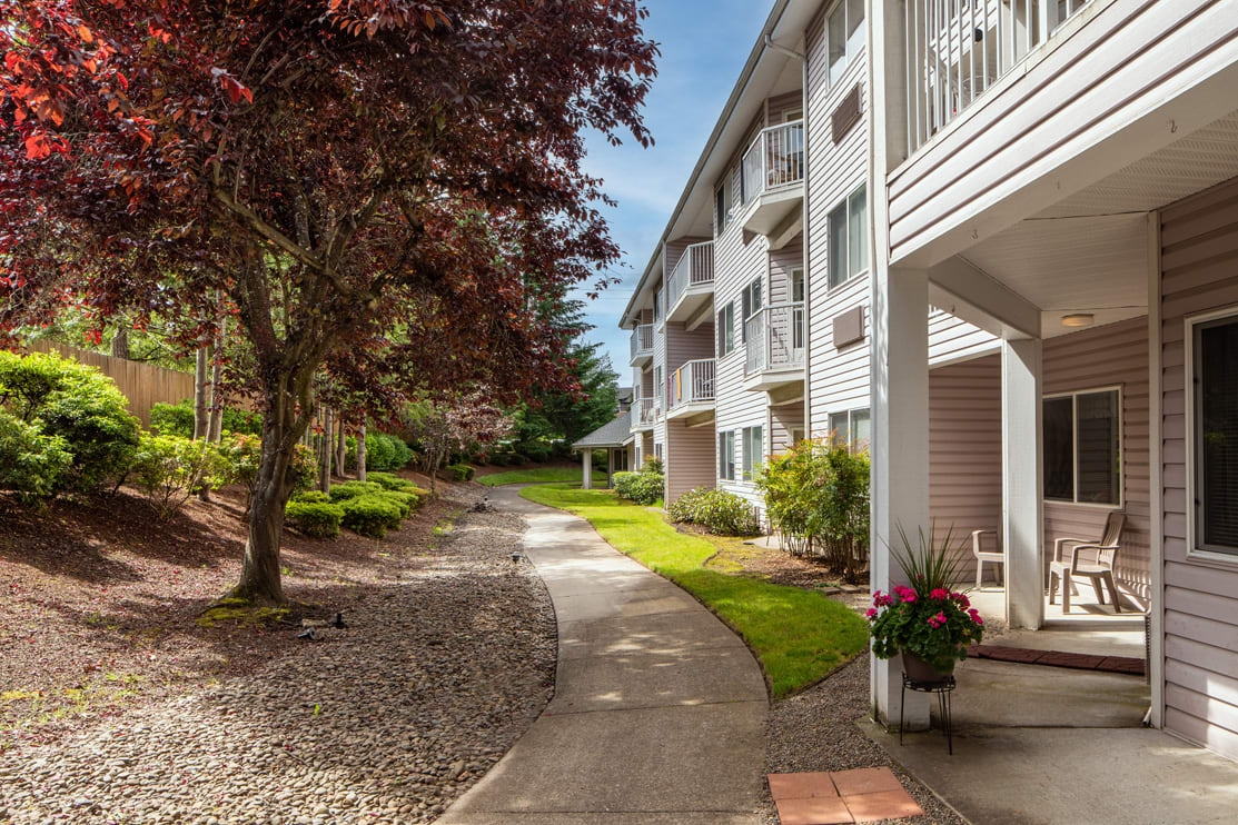 A scenic view of an apartment building with a landscaped garden and pathway.