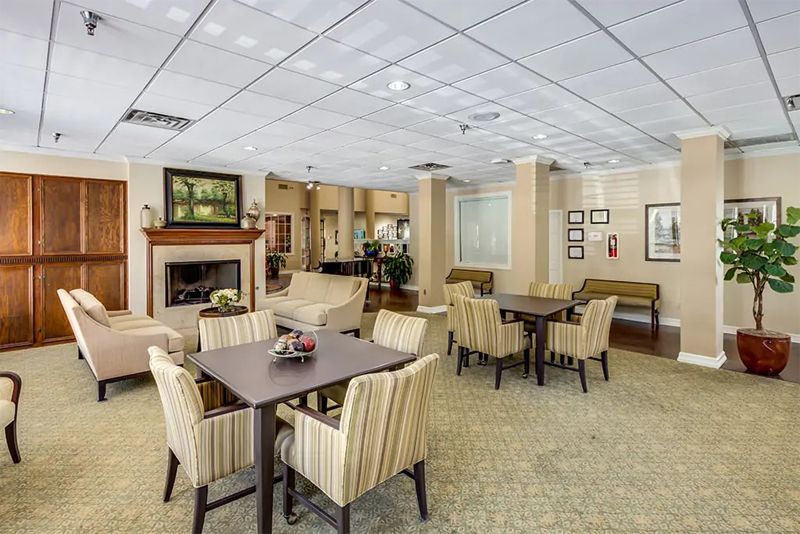 A cozy and elegantly designed lobby seating area with tables, chairs, and a fireplace.