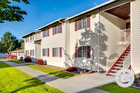 A sunny day view of a residential apartment building with landscaped surroundings.
