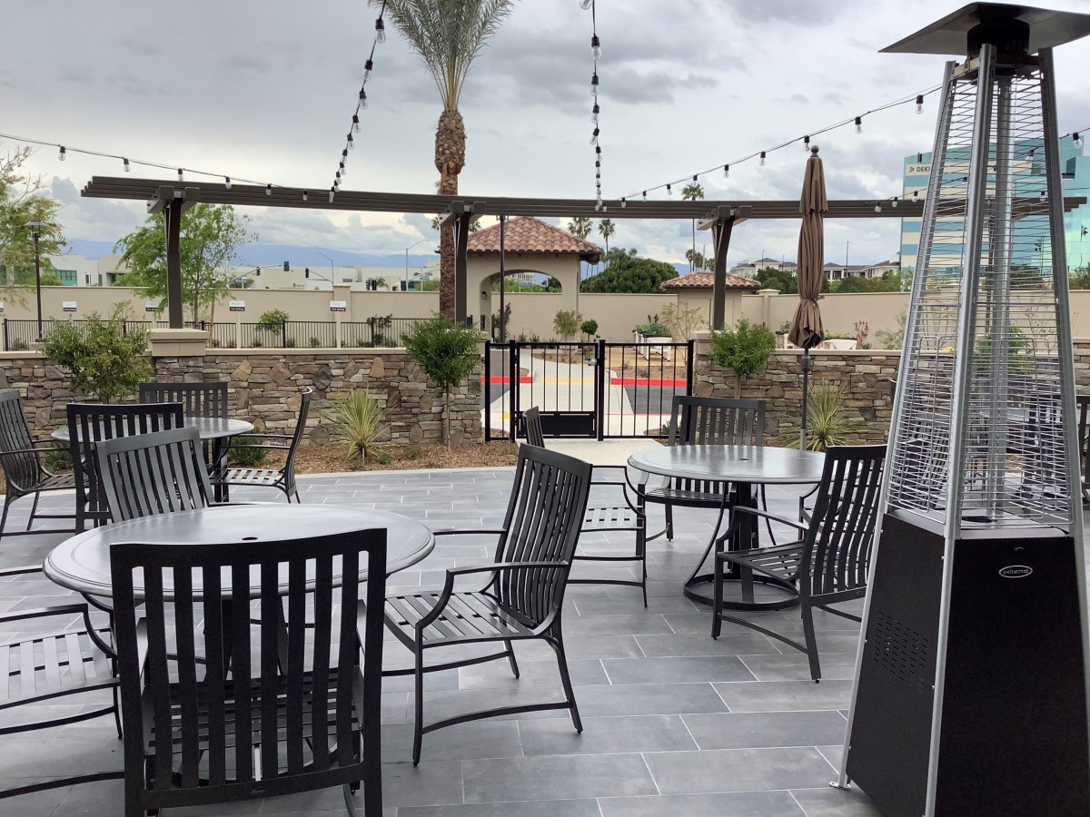 A cozy outdoor patio with tables and chairs under a cloudy sky.