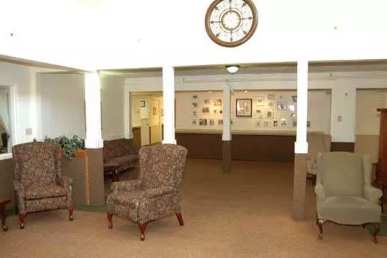 A view of a lobby area featuring armchairs, a large wall clock, and decorative items on the walls.