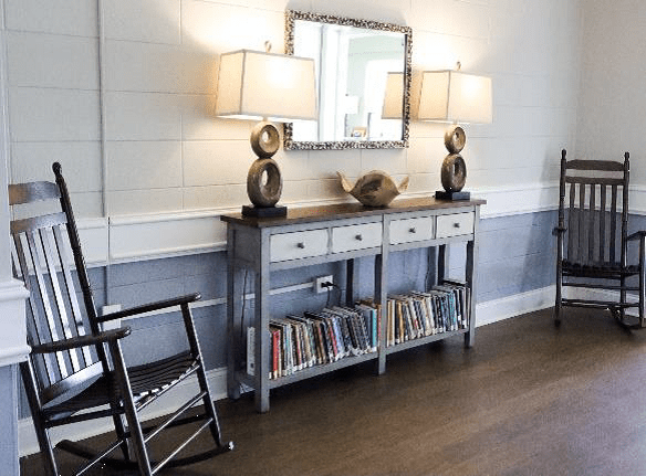 A cozy interior with a console table, lamps, mirror, and bookshelf beneath.