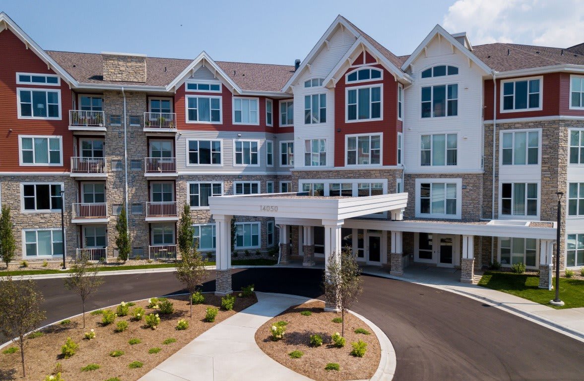 A modern residential building with an entrance driveway and landscaped surroundings.