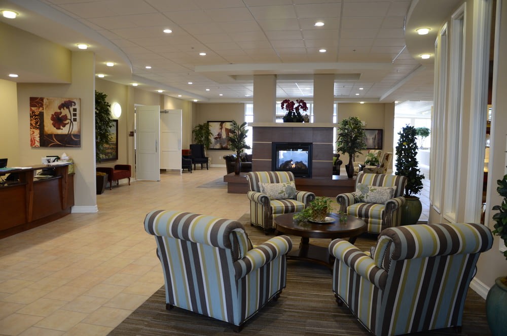 A spacious hotel lobby featuring a seating area with striped chairs and a central fireplace.