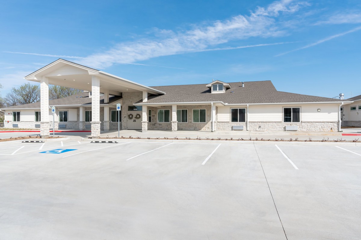 A single-story building with a parking lot under a clear blue sky.